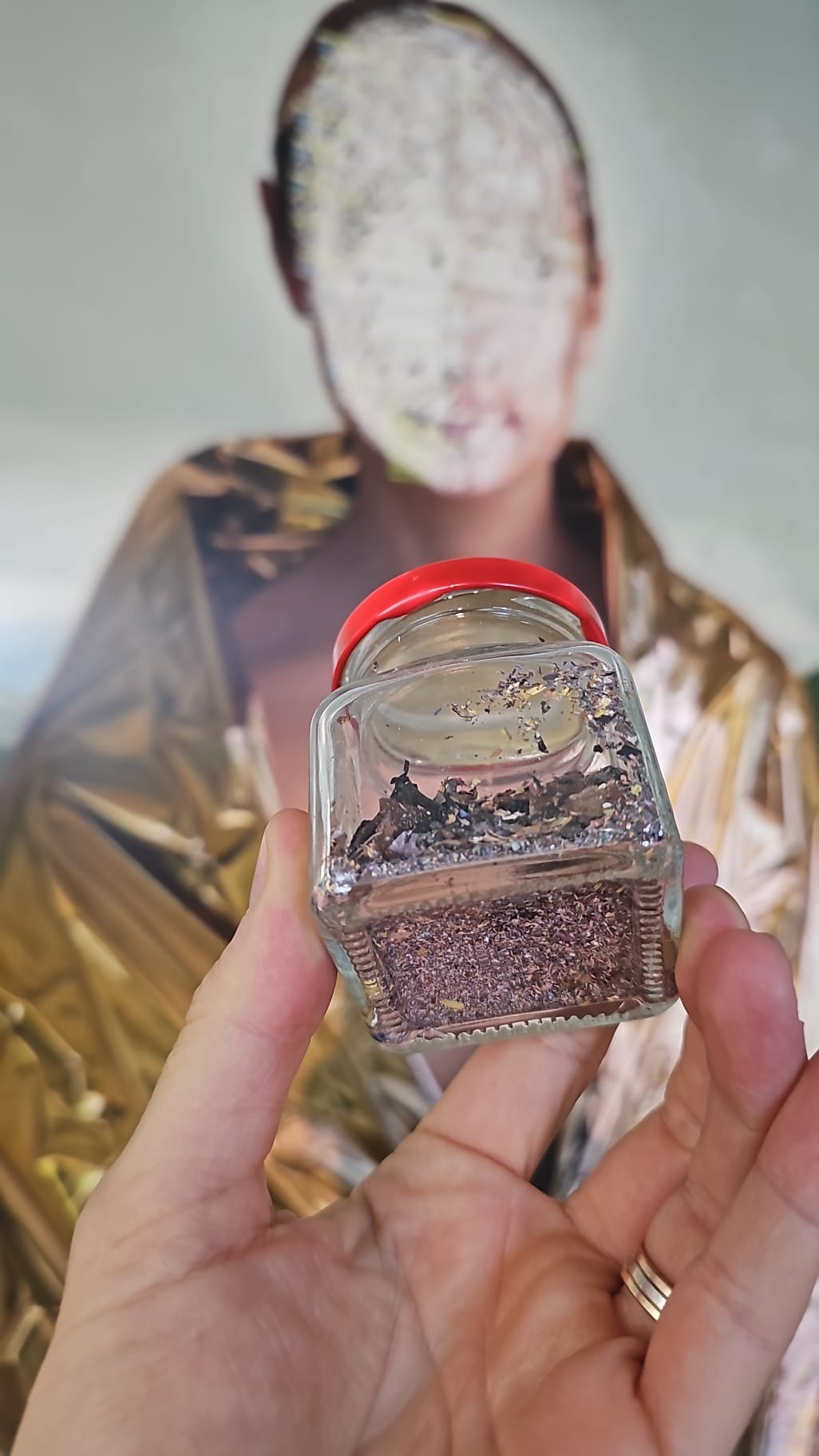 Jar containing the paint scratched from the portrait, held in front of the altered painting
